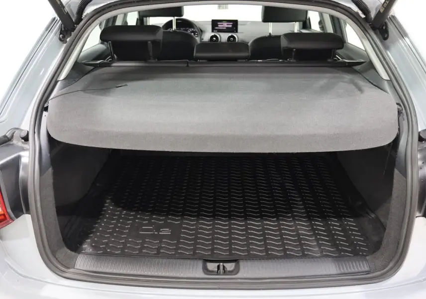 Coffre ouvert vu de l'arrière d'un Audi Q2 gris 2023 avec hayon électrique et intérieur noir.