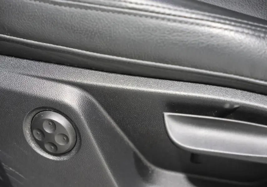 Détail des commandes de réglage du siège en cuir noir de l'Audi Q2 TFSI 110 gris, vue intérieure côté conducteur.