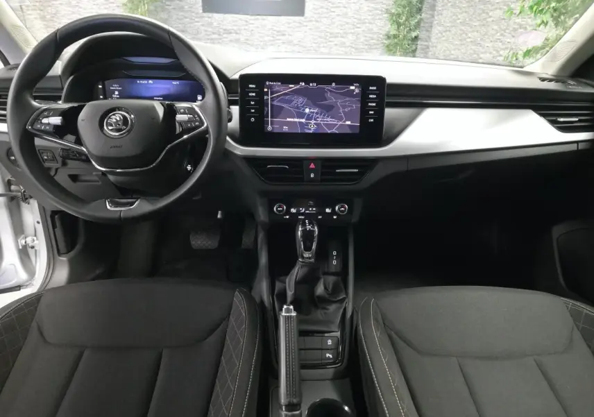 Vue intérieure avant du Skoda Kamiq 2023 avec tableau de bord noir, écran tactile central et volant multifonctions.