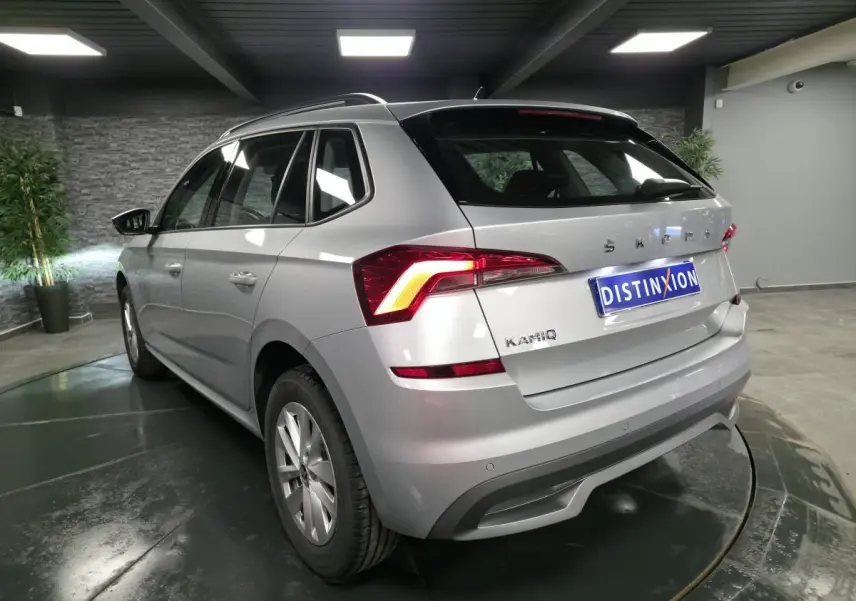 Vue 3/4 arrière droite du Skoda Kamiq gris métallisé avec feux arrière LED et jantes alliage 16 pouces en showroom.