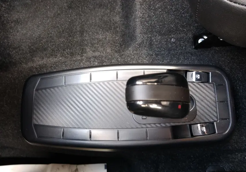 Vue plongeante sur la console centrale avec levier de vitesse noir et finition carbone dans une Ligier Myli REVO D+ MAX gris graphite.