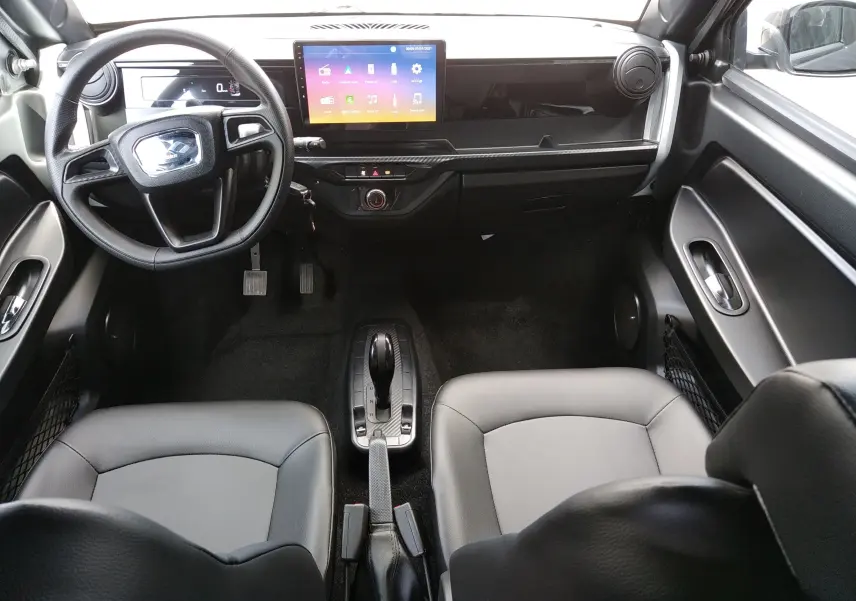 Vue intérieure avant de la Ligier Myli REVO D+ MAX 2026, avec tableau de bord noir, écran tactile central et sièges cuir noir.