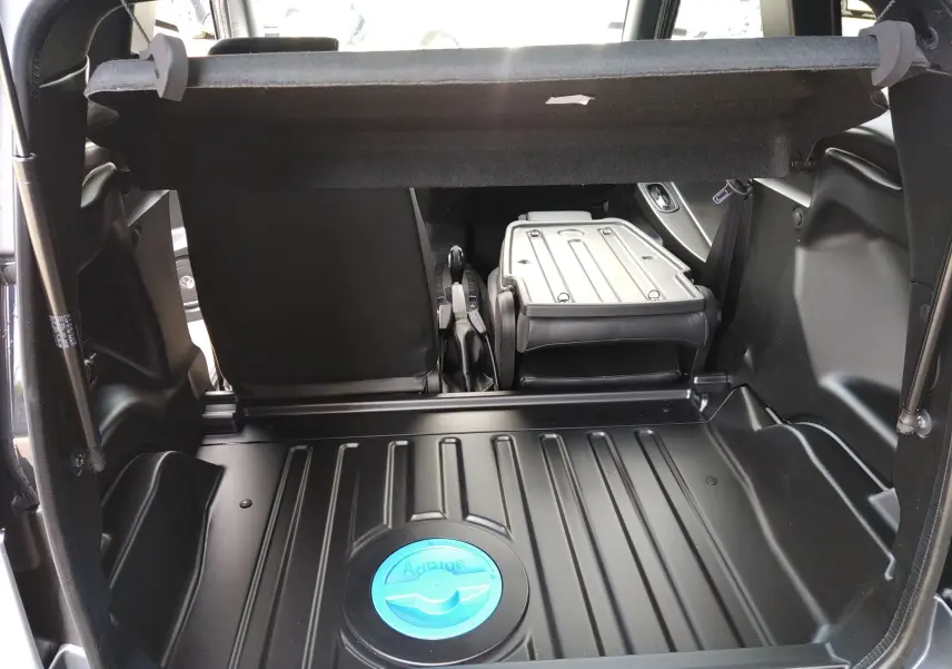 Vue intérieure du coffre ouvert du Ligier Myli REVO D+ MAX gris graphite, avec siège arrière rabattable et bouchon AdBlue visible.