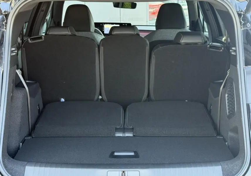 Vue arrière du coffre noir Perla du Peugeot 5008 Hybrid GT, montrant les sièges rabattus et l'espace de chargement.