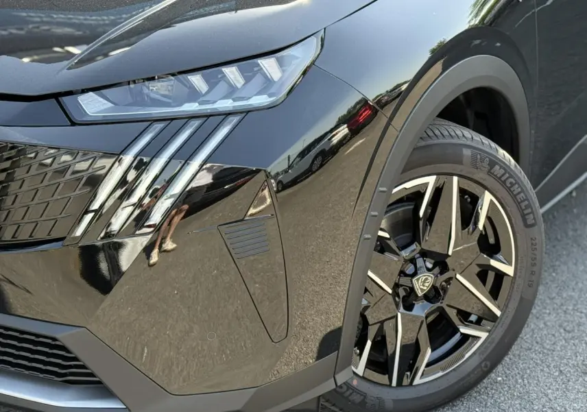 Gros plan sur l'avant droit noir Perla du Peugeot 5008 Hybrid 145 GT, mettant en valeur le phare LED et la jante alliage 19 pouces.