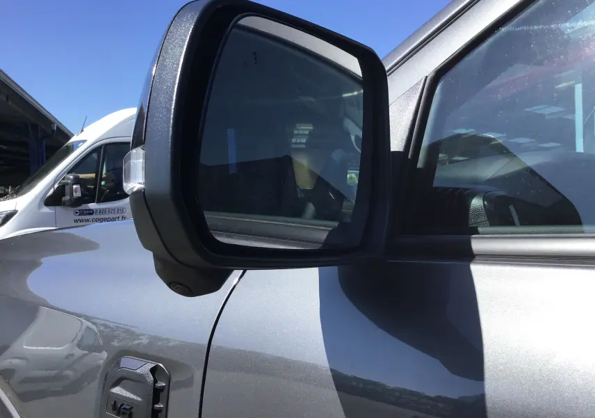 Gros plan sur le rétroviseur côté gauche d'un Ford Ranger Wildtrak gris carbone 2025 avec caméra intégrée.