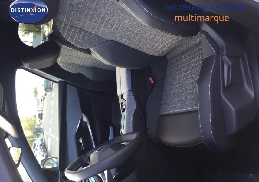 Intérieur du Peugeot 5008 Hybrid 2025, vue côté conducteur, sièges tissu gris et cuir noir avec coutures blanches.