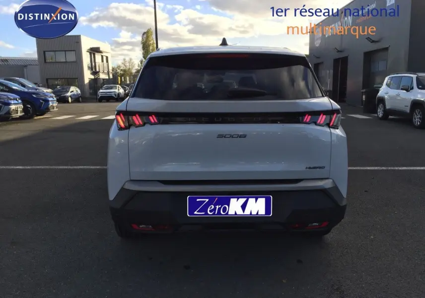 Vue arrière d'un Peugeot 5008 blanc Okenite Metal avec feux LED caractéristiques allumés sur parking extérieur.