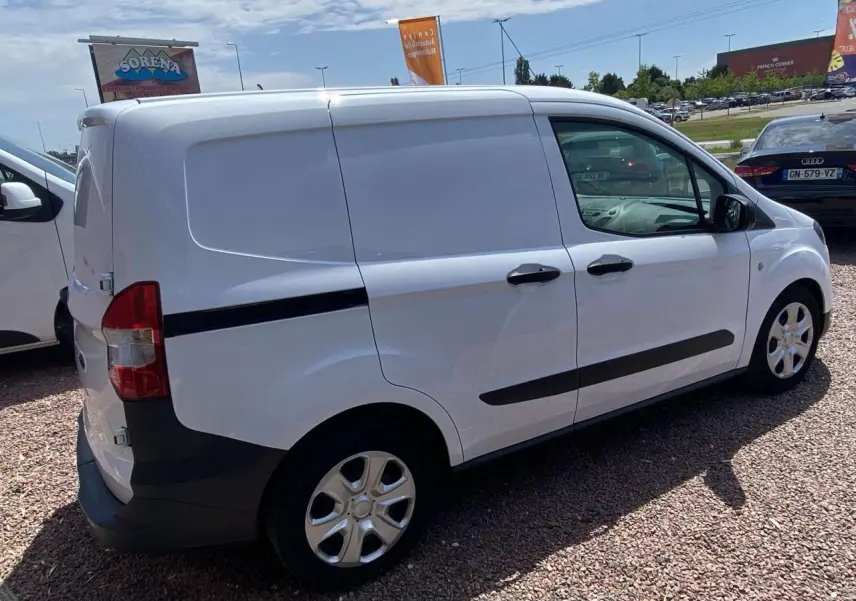 Ford Tourneo Courier blanc vu de trois quarts arrière droit, fourgon utilitaire avec porte latérale coulissante et enjoliveurs cache moyeu.