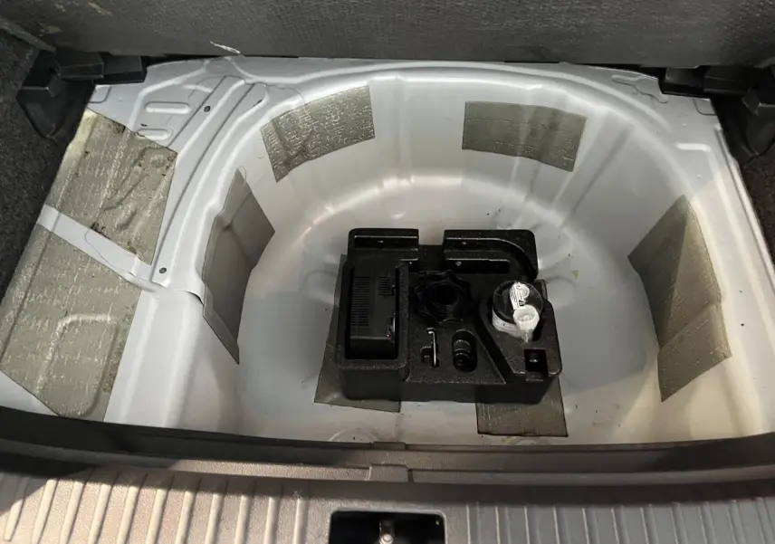 Coffre ouvert du SEAT Arona blanc Nevada 2024 montrant le rangement sous plancher avec kit de réparation pneus.