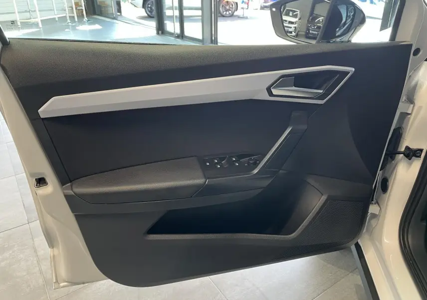 Vue intérieure de la porte avant gauche blanche du SEAT Arona 2024 avec commandes de vitres et rétroviseur.