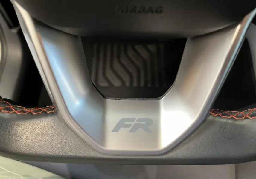 Gros plan sur le volant cuir noir du SEAT Arona FR 2024 avec surpiqûres rouges et logo FR au centre.