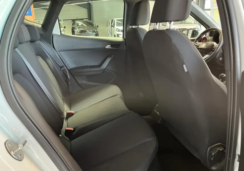Vue intérieure côté gauche de la banquette arrière noire du SEAT Arona blanc Nevada 2024 avec sièges textile ACERO.