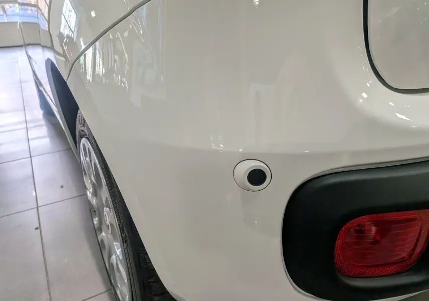 Gros plan sur l’aile arrière gauche blanche Gelato d’une Fiat Panda 1.0 Hybrid 2025 avec feu arrière et capteur de stationnement.