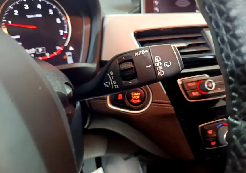 Vue rapprochée du commodo d’essuie-glace et bouton start/stop sur tableau de bord noir d’une BMW X2 2023.