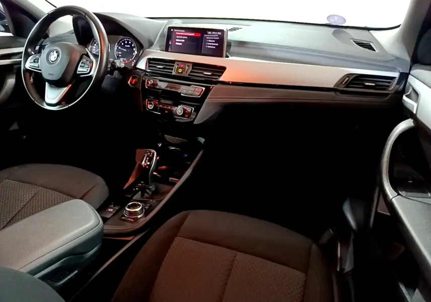 Vue intérieure avant droite du BMW X2 sDrive18i 2023, tableau de bord noir avec volant cuir alu multifonctions.