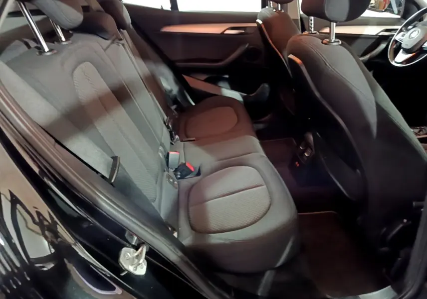Vue intérieure côté gauche sur les sièges arrière noirs et l'avant de la BMW X2 sDrive18i Lounge DKG7 2023.