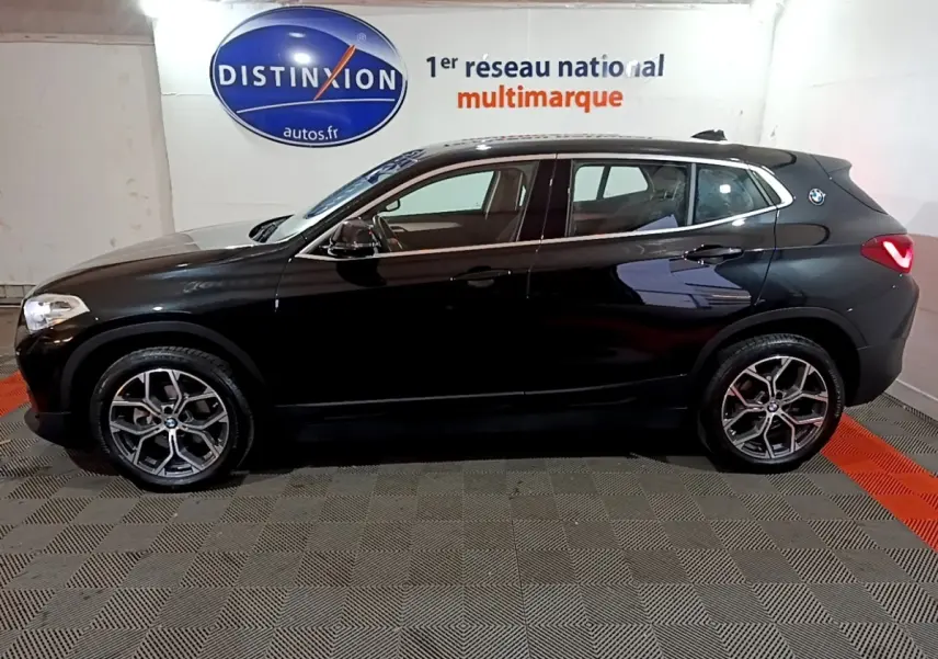 BMW X2 sDrive18i Lounge noir vue de profil côté gauche, avec jantes alliage et logo BMW sur l'aile arrière.