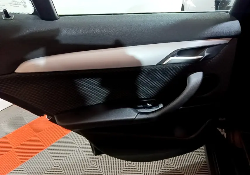 Vue rapprochée de la porte intérieure côté gauche noire avec insert gris et poignée alu d’une BMW X2 2023.