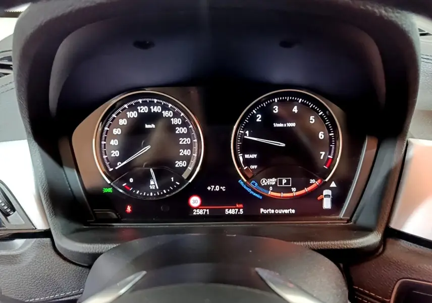 Tableau de bord numérique de BMW X2 sDrive18i 2023, affichage vitesse et compte-tours avec alertes visibles.