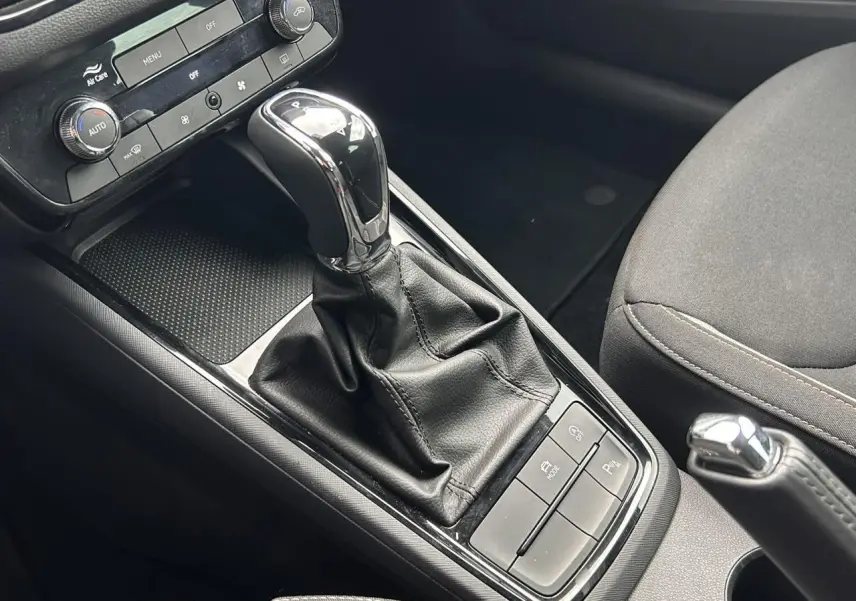 Gros plan intérieur sur la console centrale de la Skoda Scala TSI 116 DSG7 avec levier de vitesse et commandes noires.
