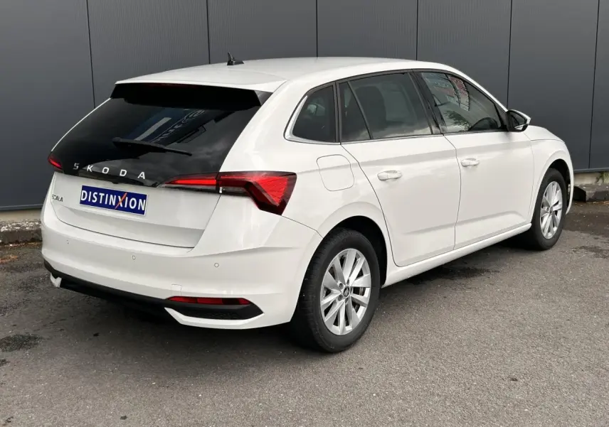 Vue 3/4 arrière droite d'une Skoda Scala blanc Candy avec lunette arrière surteintée et jantes alliage 16 pouces.