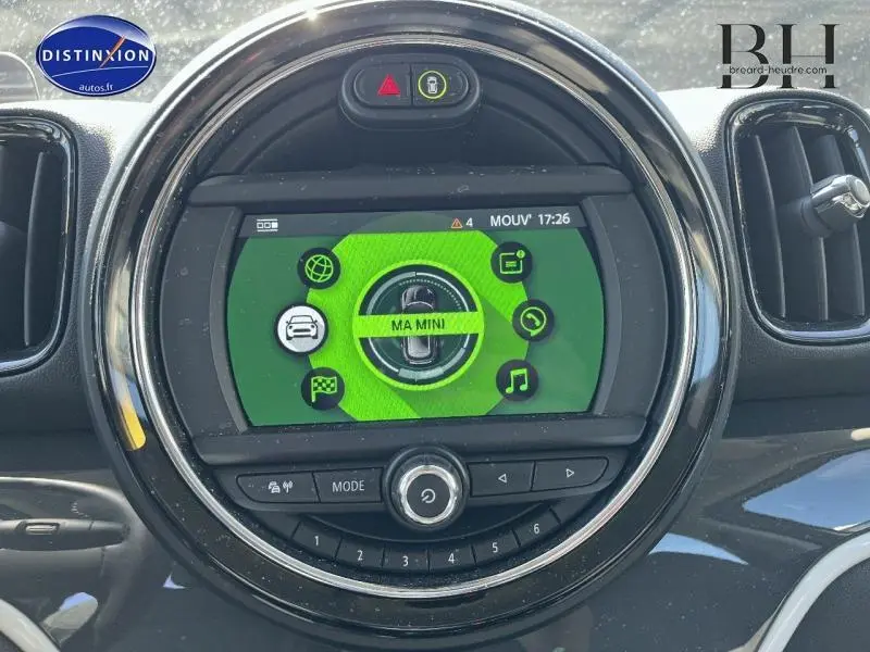 Écran central rond du tableau de bord du MINI Countryman Cooper SE avec interface verte et commandes intégrées.