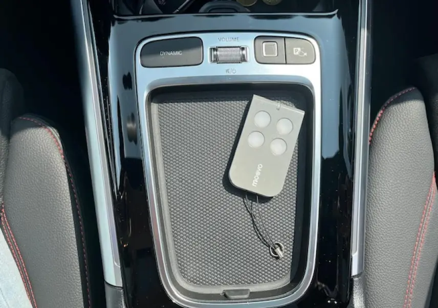 Vue plongeante sur la console centrale noire brillante du Mercedes GLA 250 e AMG Line avec télécommande posée.