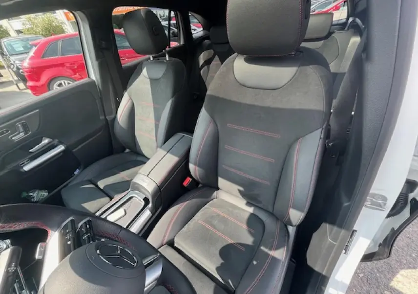 Vue intérieure côté conducteur du Mercedes GLA 250 e blanc, sièges sport en alcantara noir avec surpiqûres rouges.