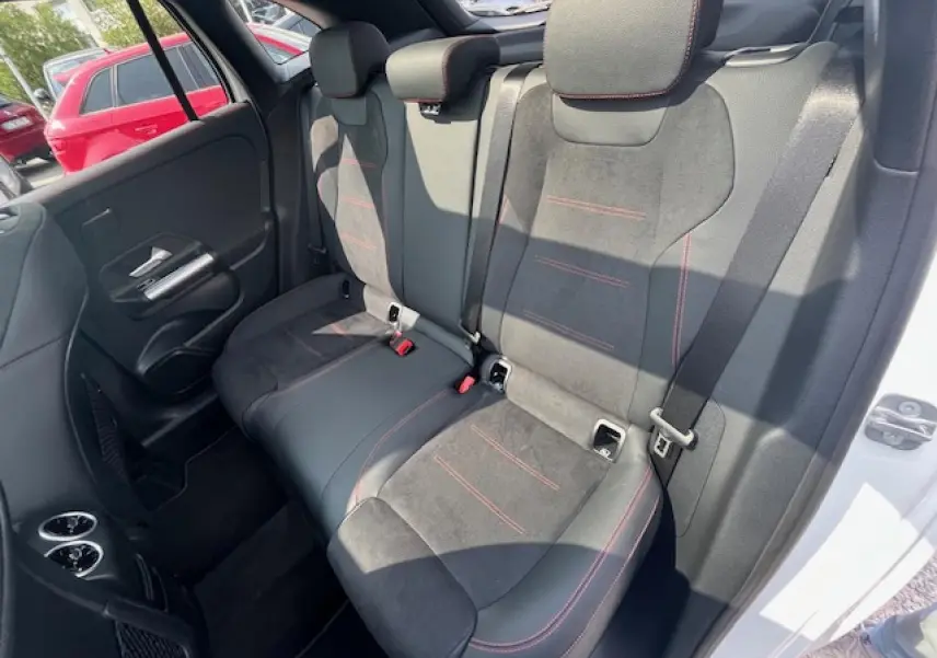 Vue côté droit des sièges arrière en alcantara noir avec surpiqûres rouges dans une Mercedes GLA 250 e hybride blanche 2024.