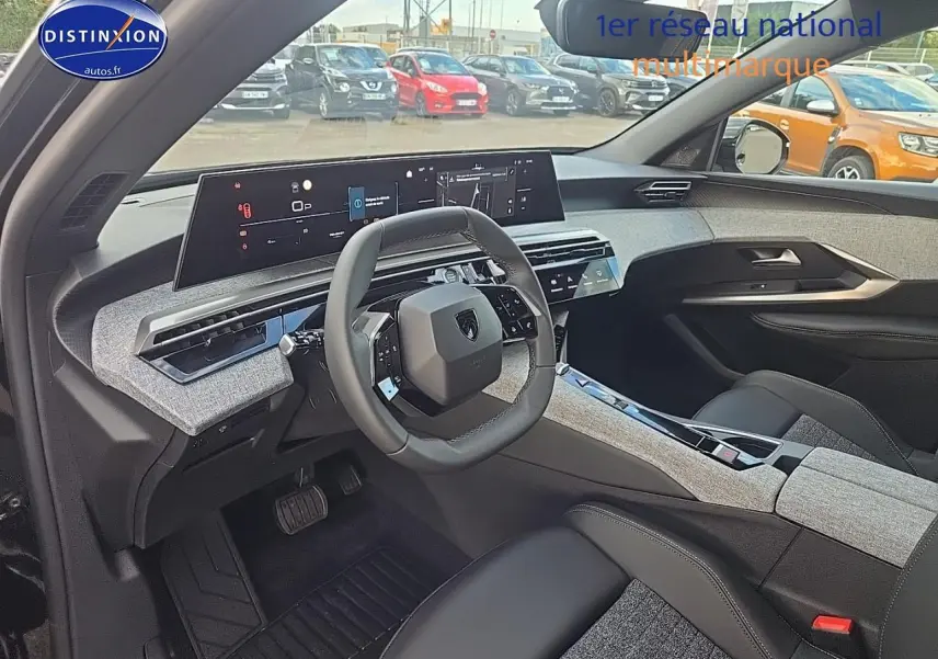 Intérieur du Peugeot 3008 2025 vu côté conducteur, volant cuir et tableau de bord numérique large avec finitions tissu gris.