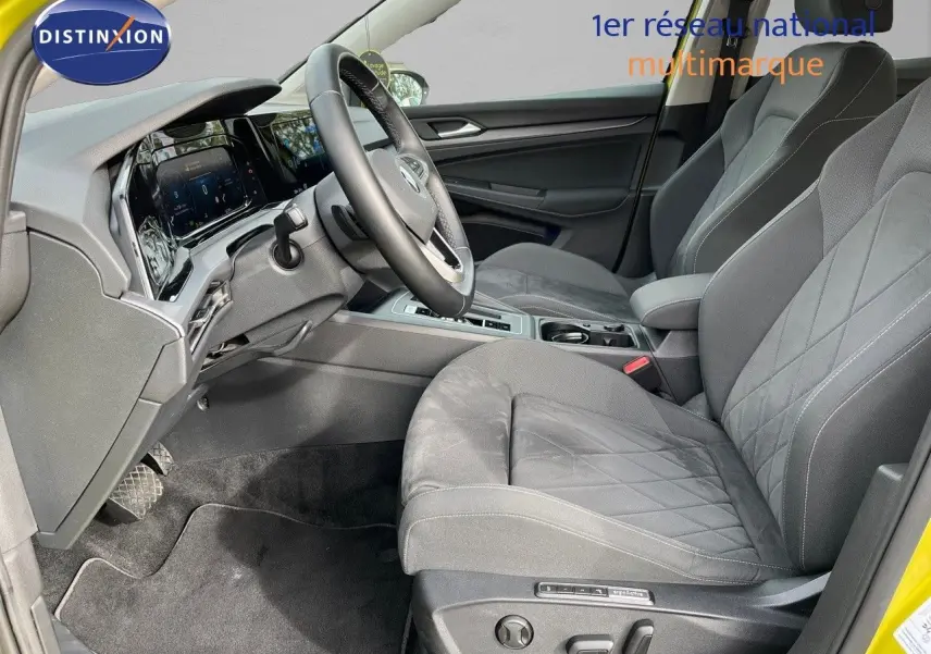 Vue intérieure côté conducteur de la Volkswagen Golf jaune 2020, sièges gris avec surpiqûres et tableau de bord digital.