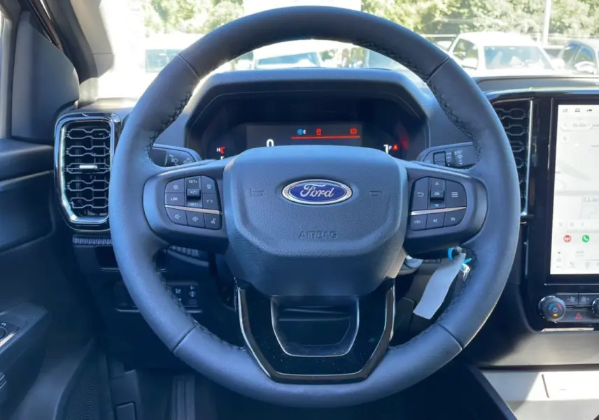 Vue rapprochée du volant noir du Ford Ranger 2025 TDCI 170 BVA XLT avec commandes intégrées et tableau de bord digital.