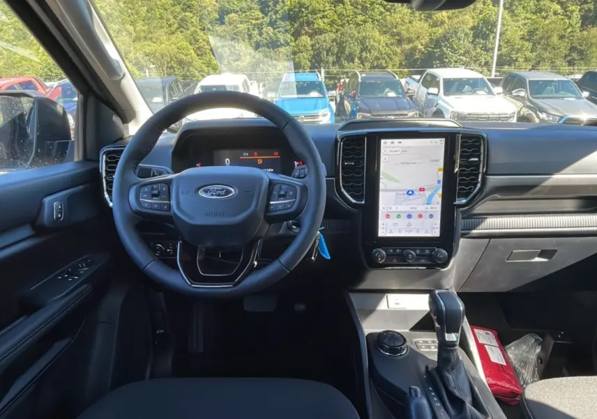 Intérieur du Ford Ranger 2025 noir shadow, vue frontale du poste de conduite avec écran tactile et volant multifonction.