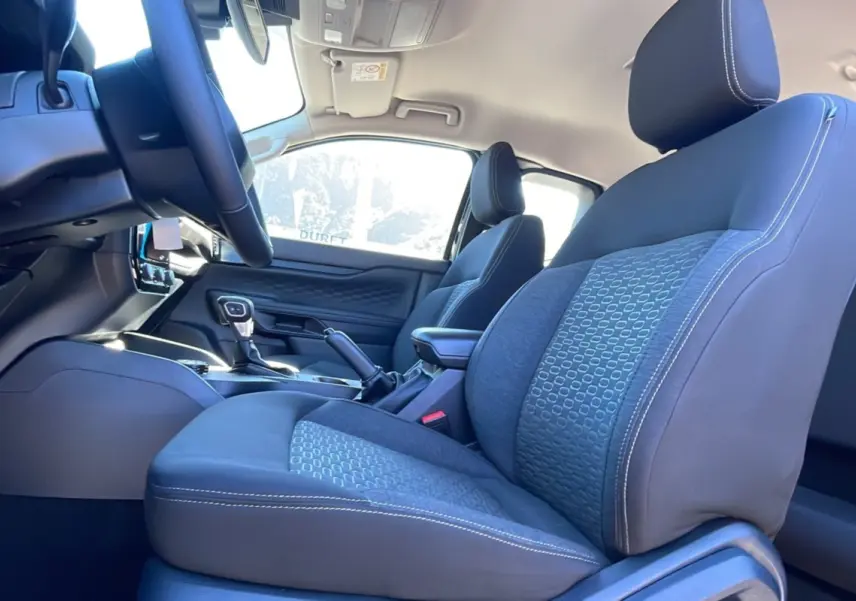 Intérieur du Ford Ranger 2025, vue côté conducteur sur les sièges tissu gris avec coutures blanches et console centrale.