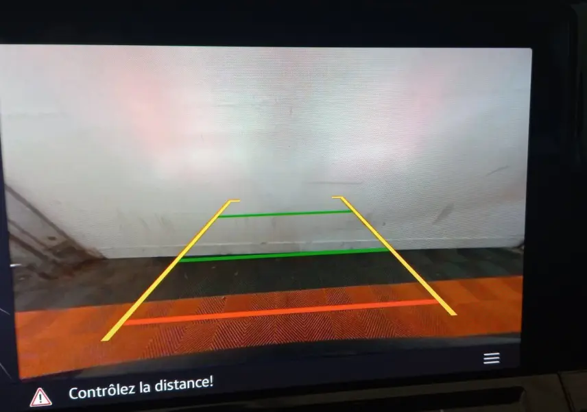 Affichage caméra de recul de la Volkswagen Golf 2022 montrant les lignes de guidage colorées sur fond de mur blanc.