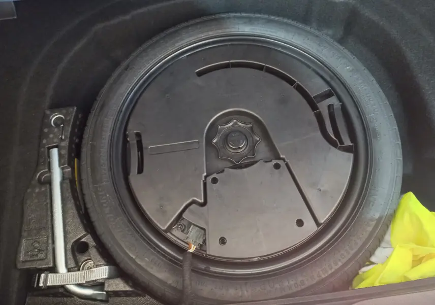 Gros plan sur la roue galette noire et les outils de secours dans le coffre d'une Volkswagen Golf bleue 2022