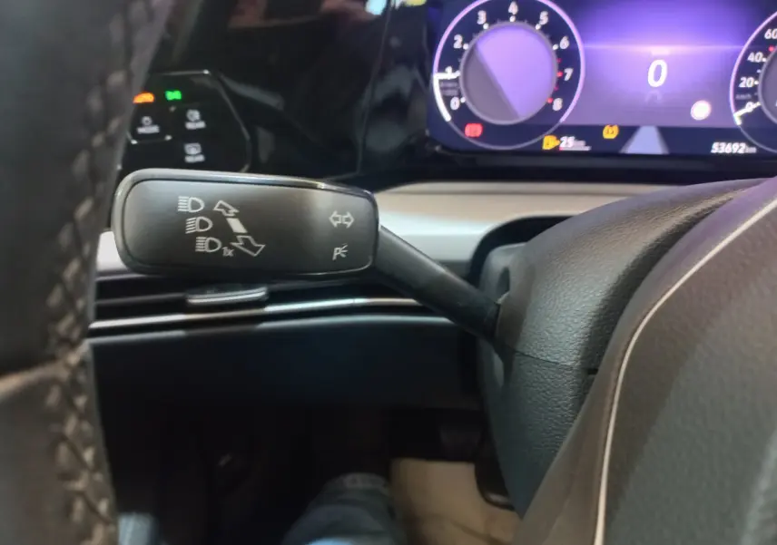 Gros plan sur la commande des feux et clignotants à gauche du volant dans une Volkswagen Golf bleue de 2022.