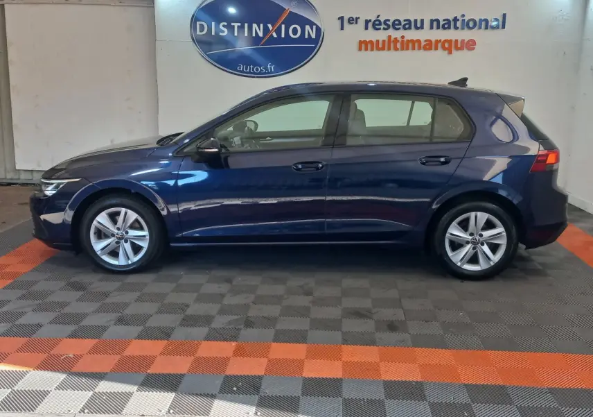 Profil côté gauche d'une Volkswagen Golf 1.5 bleu foncé, avec jantes alliage et feux arrière LED visibles.