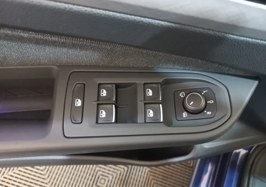 Gros plan sur les commandes de lève-vitres et réglage des rétroviseurs côté conducteur d'une Volkswagen Golf bleu 2022.