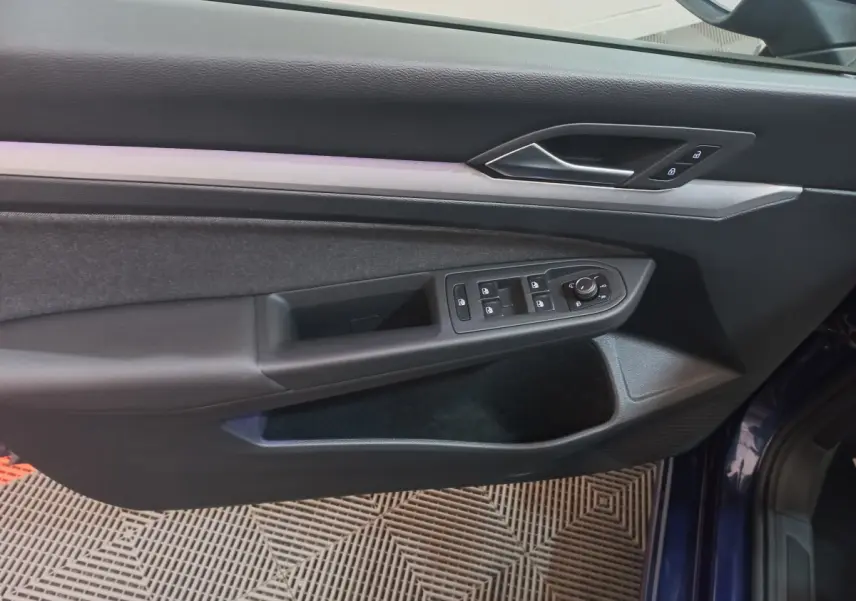 Vue rapprochée de la porte côté gauche d'une Volkswagen Golf 2022 bleu, avec commandes de vitres et verrouillage intégrées.