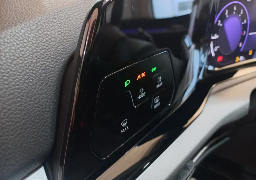 Gros plan sur le tableau de bord noir brillant de la Volkswagen Golf 2022 avec commandes d'éclairage et affichage digital violet.