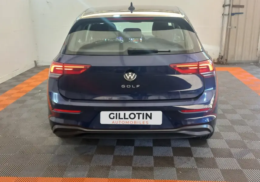 Vue arrière d'une Volkswagen Golf bleue 2022 avec feux LED allumés dans un garage intérieur.