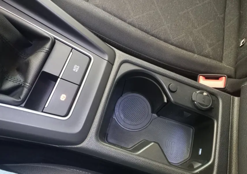 Gros plan sur la console centrale noire de la Volkswagen Golf 2022, avec zone de recharge sans fil et prise 12V visible.