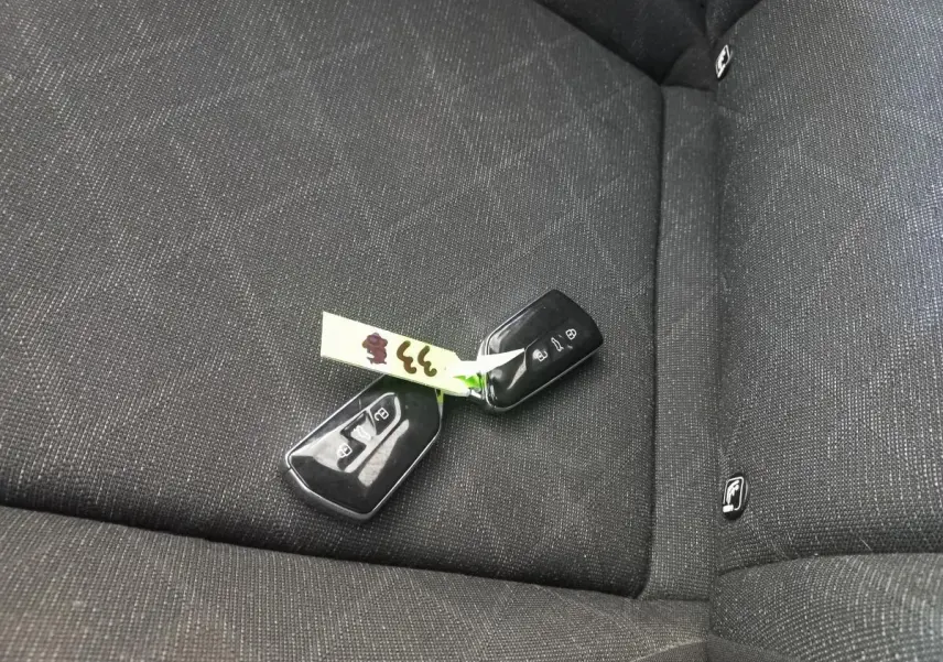 Clé de voiture Volkswagen Golf posée sur la banquette arrière en tissu gris foncé à motifs discrets.