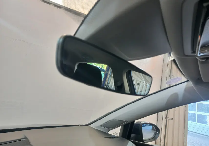 Vue intérieure côté conducteur de la Volkswagen Golf bleu 2022, avec rétroviseur central et extérieur visibles.