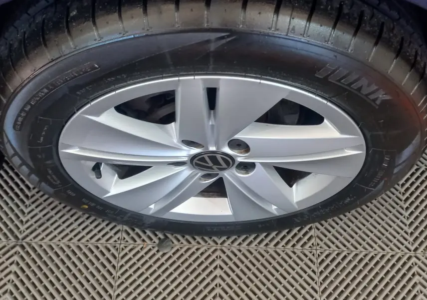 Gros plan sur la jante argentée avec logo Volkswagen d'une Golf bleu, vue du dessus sur le pneu noir.