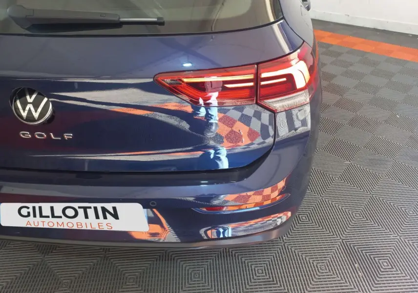 Vue arrière droite d'une Volkswagen Golf bleue avec feux LED et logo VW bien visibles.
