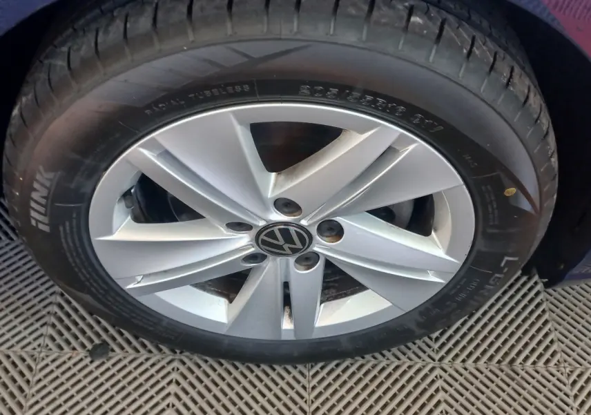 Gros plan sur la roue avant droite de la Volkswagen Golf bleu, avec jante alliage argentée et logo VW central.