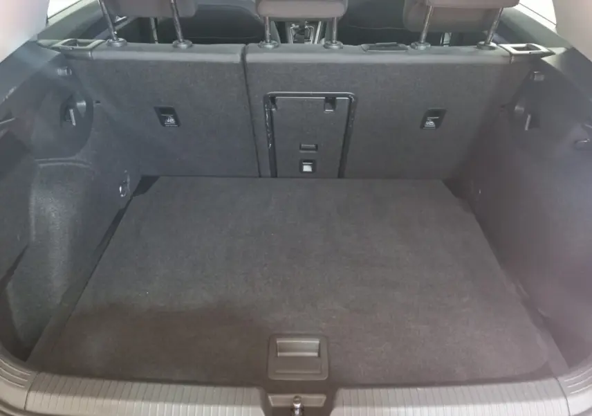 Coffre spacieux de Volkswagen Golf 2022 vu de l'arrière, revêtement intérieur gris foncé et banquette arrière rabattue partiellement.